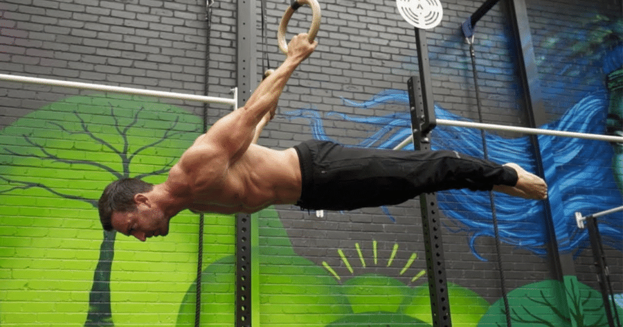Atleta in posizione di back lever alla sbarra
